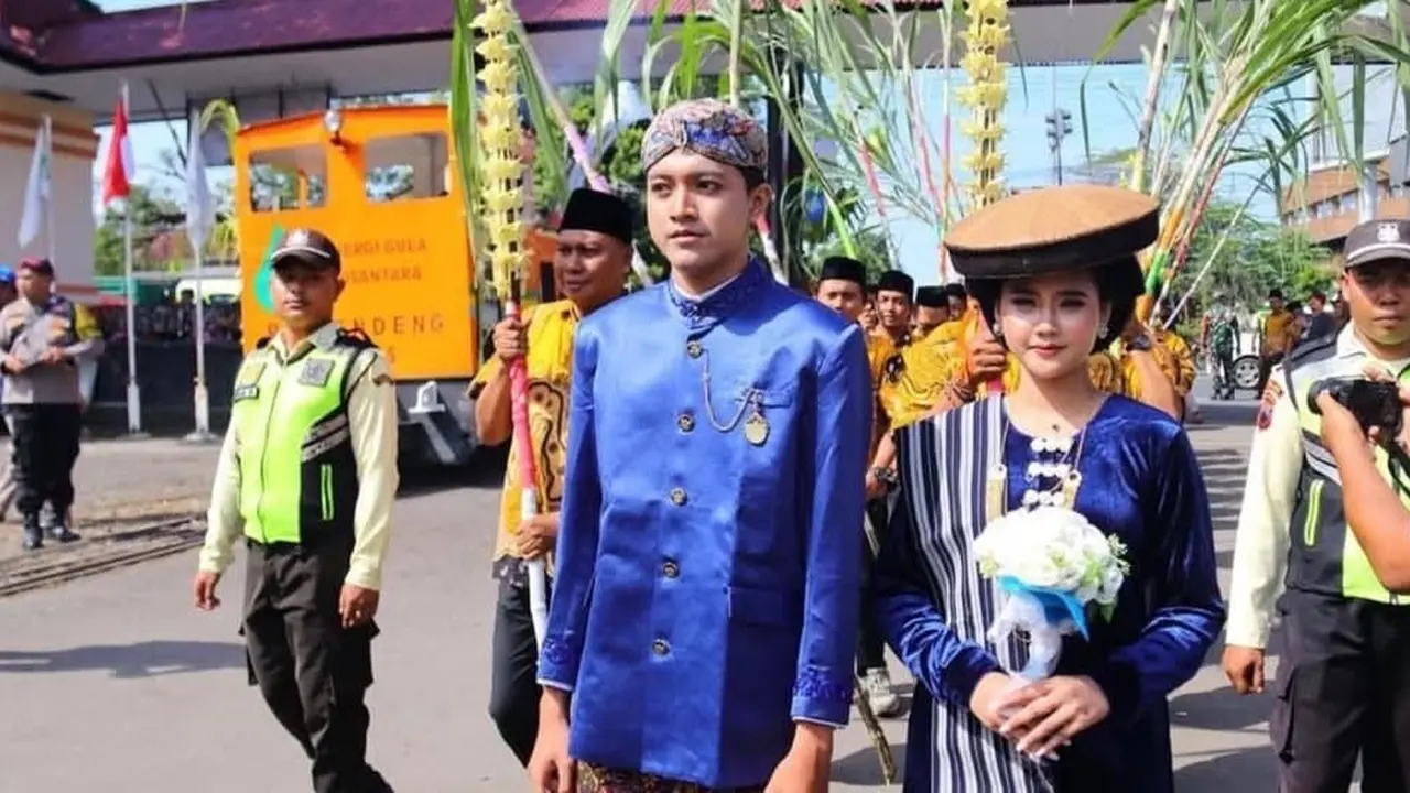 Sepasang pengantin pria dan wanita diiringi dua batang tebu di belakangnya, dikirab menandai prosesi manten tebu di PG Rendeng Kudus. (Liputan6.com/Arief Pramono)
