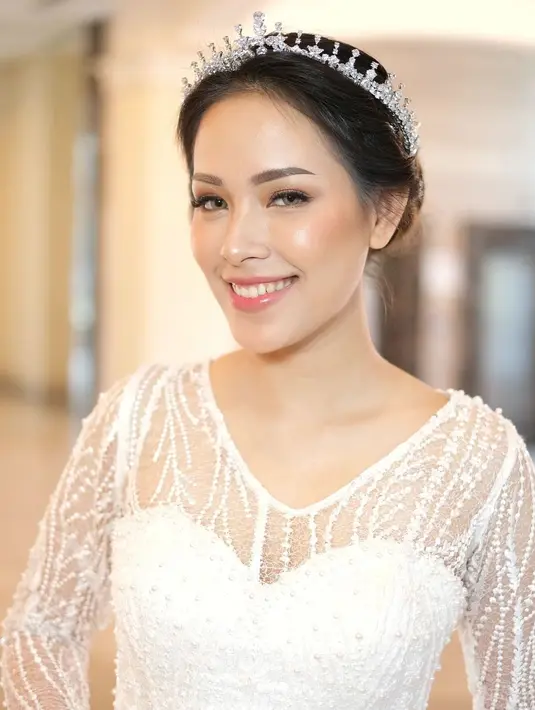 Rambutnya ditata bergaya updo, ditambah dengan tiara dari @amitiejewelry yang menghiasi kepalanya. Membuat penampilan ibu tiga anak ini semakin paripurna. [Foto: IG/@kairos_works/@byantonius]