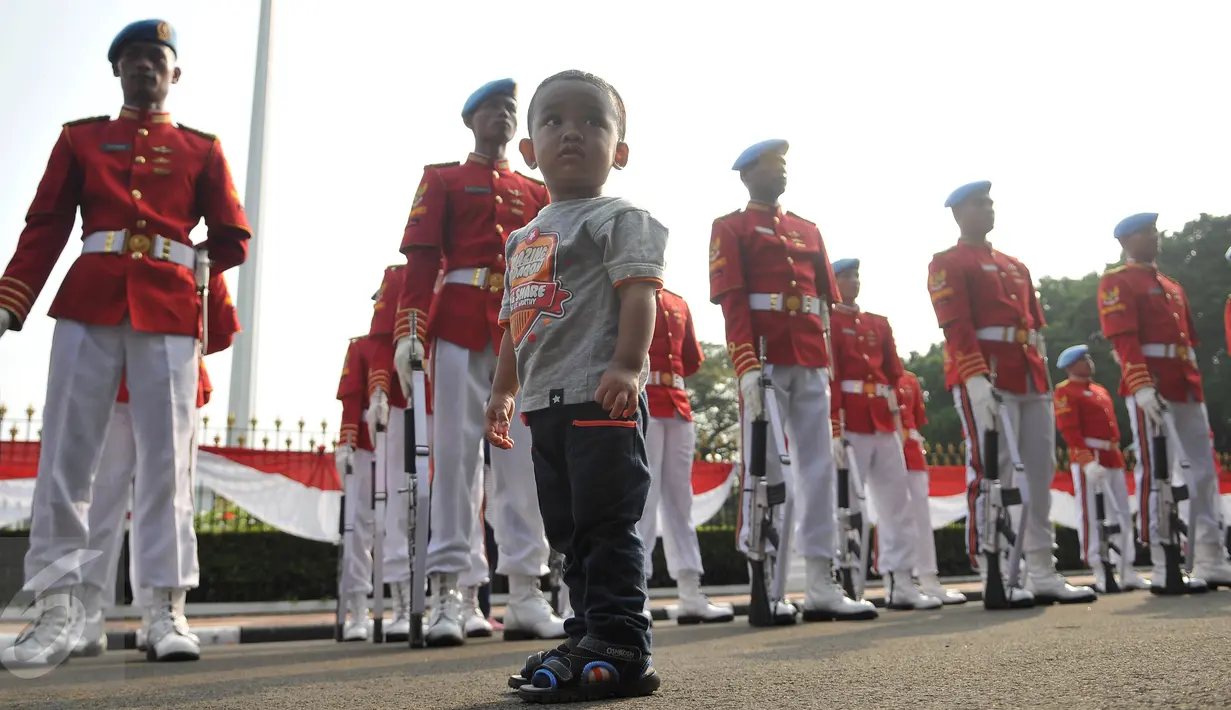 Seorang anak berdiri di depan Pasukan Pengaman Presiden di depan Istana Negara, Miggu (17/7). Prosesi pergantian pasukan penjaga Istana Negara ini akan dijadikan objek atraksi wisata baru bagi masyarakat. (Liputan6.com/Gempur M Surya)