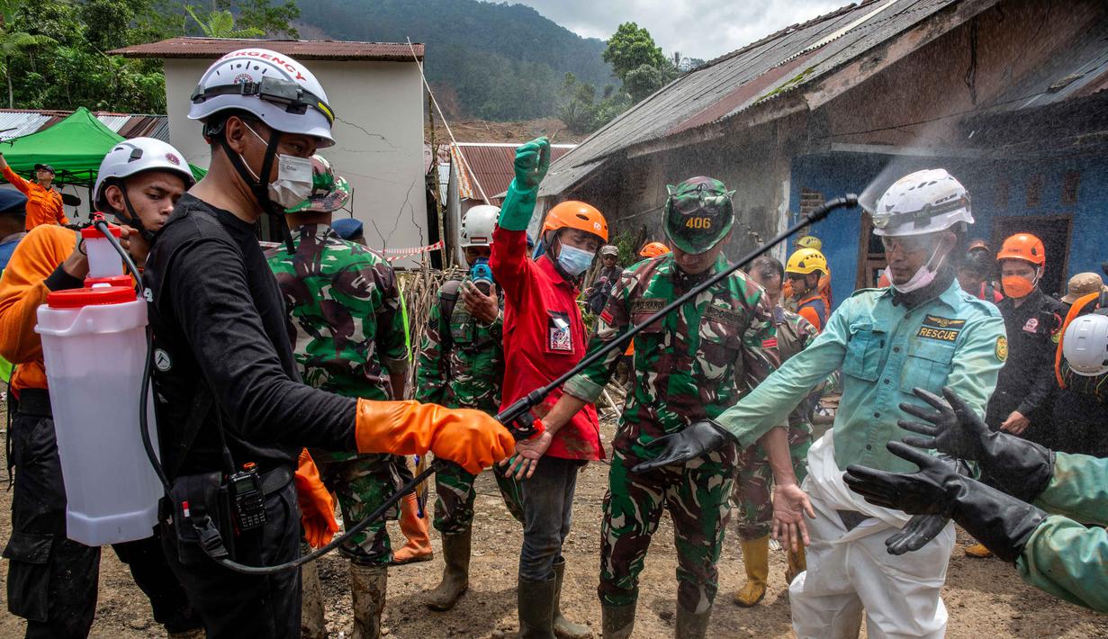 Upaya pencarian juga dibantu anjing pelacak untuk mencari posisi korban. Tampak dalam foto, petugas penyelamat disemprot disinfektan setelah membawa korban dalam operasi pencarian di lokasi longsor di Desa Situkung, Banjarnegara, Jawa Tengah, pada 20 November 2025. (DEVI RAHMAN/AFP)