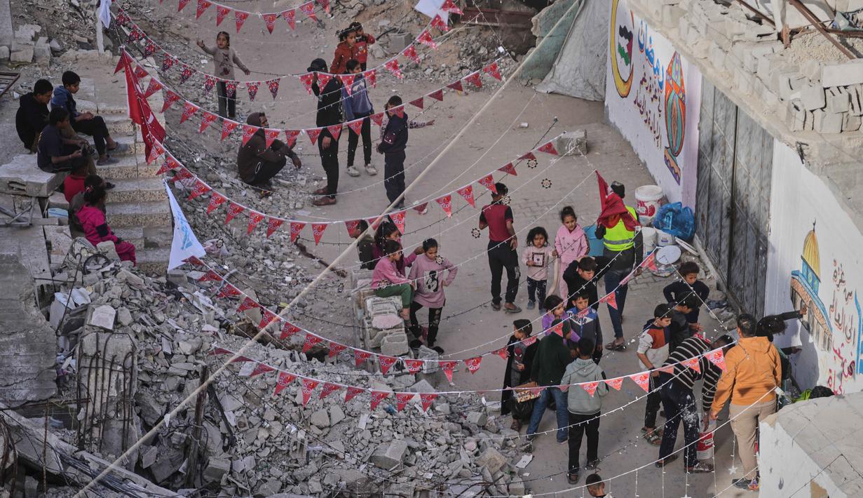 Meski hidup dalam keterbatasan, warga Palestina di Gaza tetap berupaya menghidupkan suasana Ramadan dengan beragam kreativitas. Tampa dalam foto, warga Palestina menggantungkan hiasan Ramadan di samping reruntuhan rumah yang hancur di Khan Younis, Jalur Gaza selatan, Minggu 15 Februari 2026. (AP Photo/Abdel Kareem Hana)