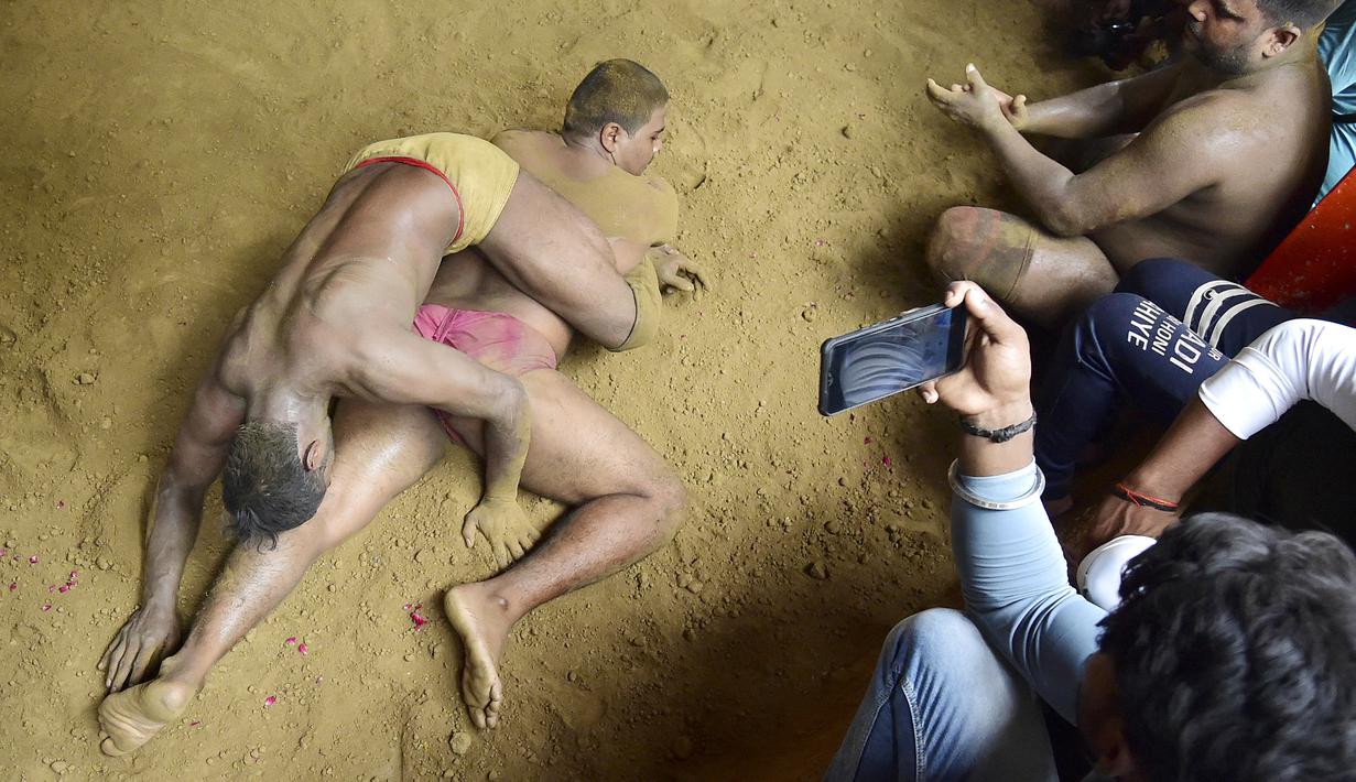 Pegulat beraksi dalam pertandingan gulat tradisional di klub gulat Loknath Vyayamsala di Prayagraj, India, (21/8/2023). Acara tersebut untuk merayakan festival Hindu Nag Panchami. (AFP/Sanjay kanojia)
