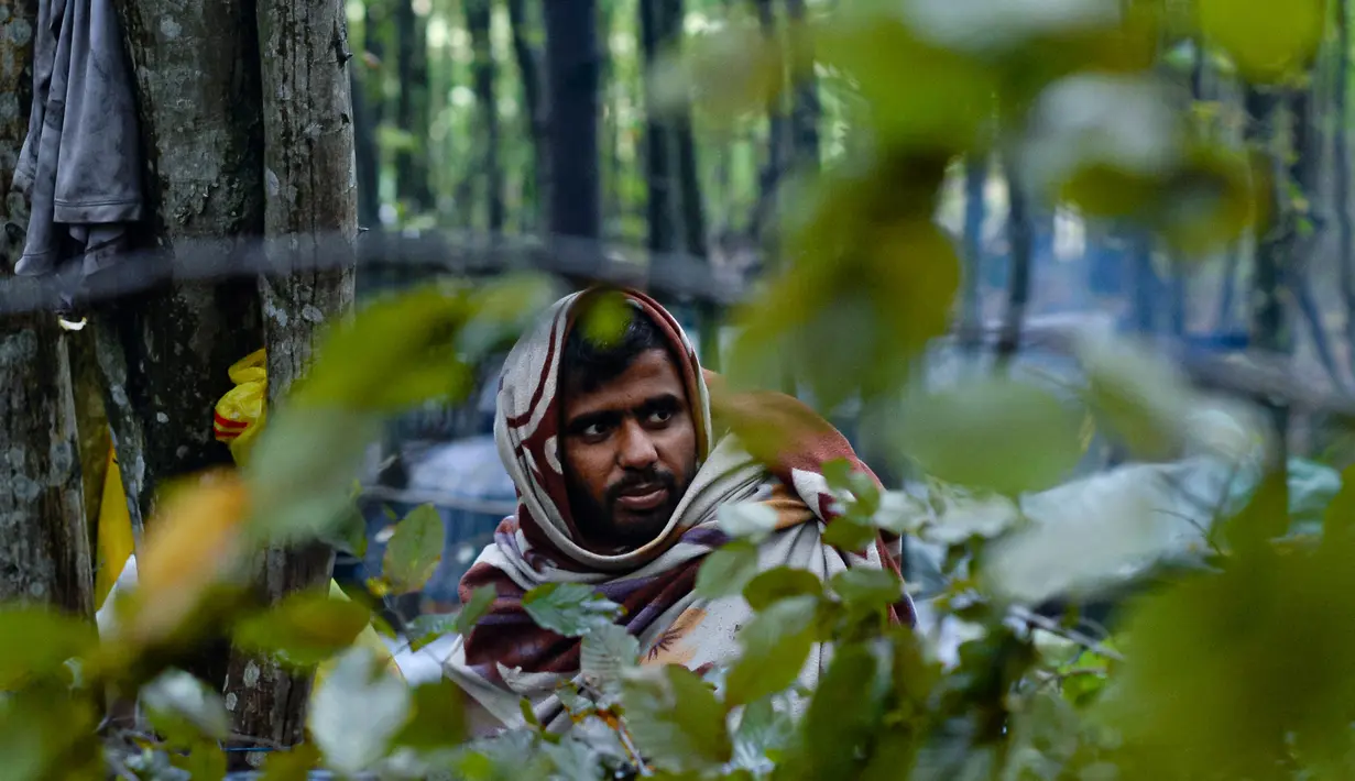 Seorang migran pria yang terbungkus selimut duduk di kamp darurat di hutan di luar Velika Kladusa, Bosnia pada 26 September 2020. Kebanyakan imigran dan pengungsi di Bosnia berasal dari Timur Tengah, Afrika dan Asia. (AP Photo/Kemal Softic)