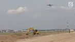Pesawat melintas di atas proyek pembangunan runway dan taxiway 3 di Bandara Soekarno-Hatta, Tangerang, Kamis (21/6). Pembangunan taxiway dan runway ketiga dapat membantu mengurai lalu lintas udara yang kian padat di Soetta. (Liputan6.com/Angga Yuniar)