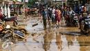 Warga dan pengendara motor melintas di sepanjang jalan yang dipenuhi lumpur di komplek Pondok Gede Permai Jatiasih, Bekasi, Jumat (22/04).Banjir yang telah merendam ratusan rumah warga mengakibatkan air lumpur mengendap. (Liputan6.com/Fery Pradolo)
