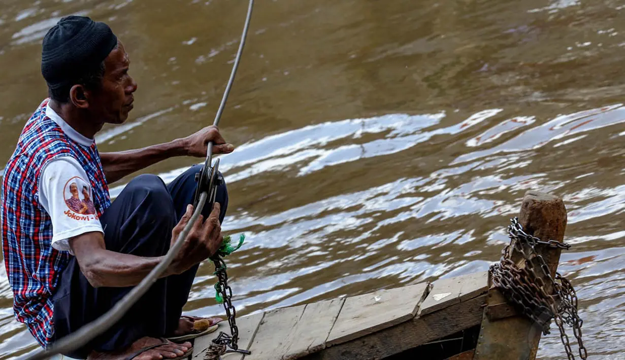 Tukang perahu eret tampak sedang menunggu penumpang di atas perahu tuanya di sungai Ciliwung, Manggarai, Jakarta, Kamis (24/4/14). (Liputan6.com/Faizal Fanani)