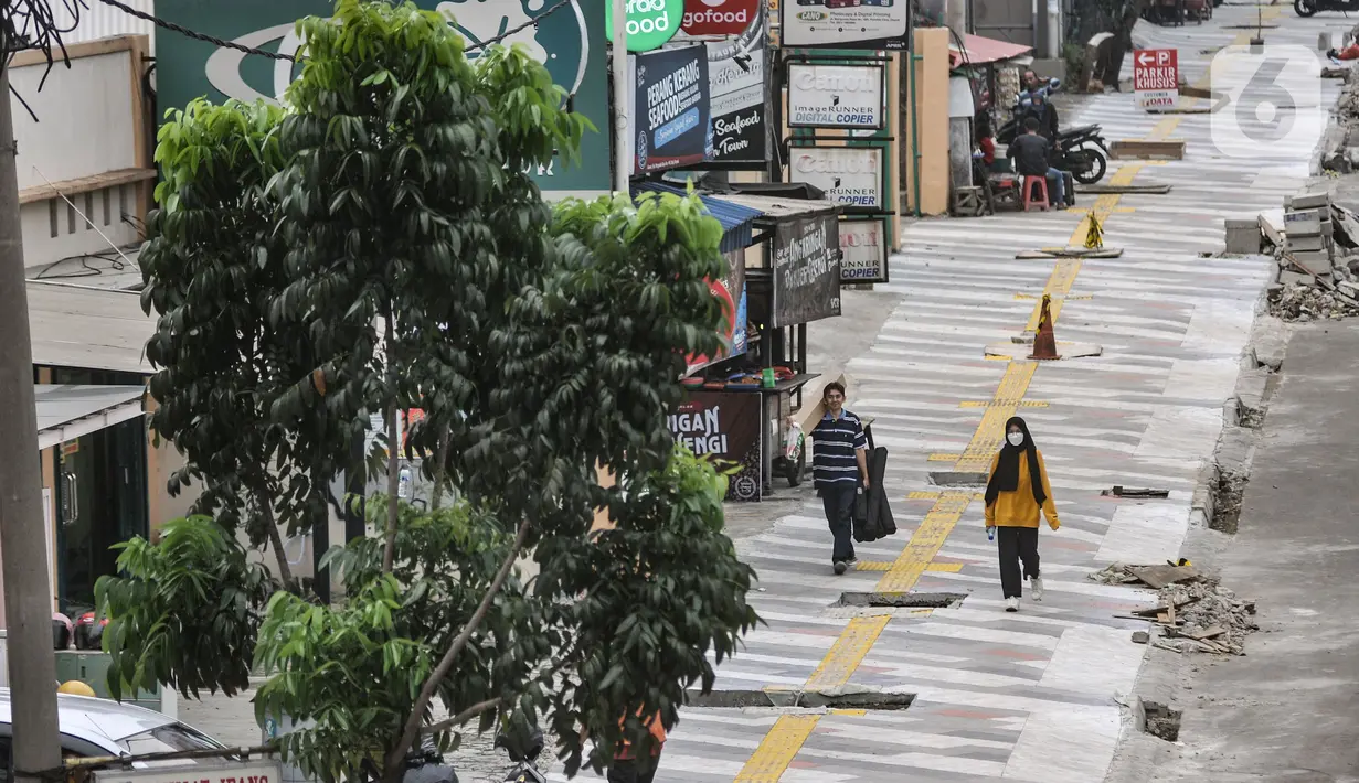 Pejalan kaki saat melintasi trotoar yang tengah direvitalisasi di Jalan Margonda Raya, Depok, Jawa Barat, Minggu (4/12/2022). Penataan trotoar di Jalan Raya Margonda, Depok, mengusung konsep instagramable. Konsep tersebut sebagai upaya meningkatkan minat masyarakat untuk berjalan kaki.(merdeka.com/Iqbal S Nugroho)
