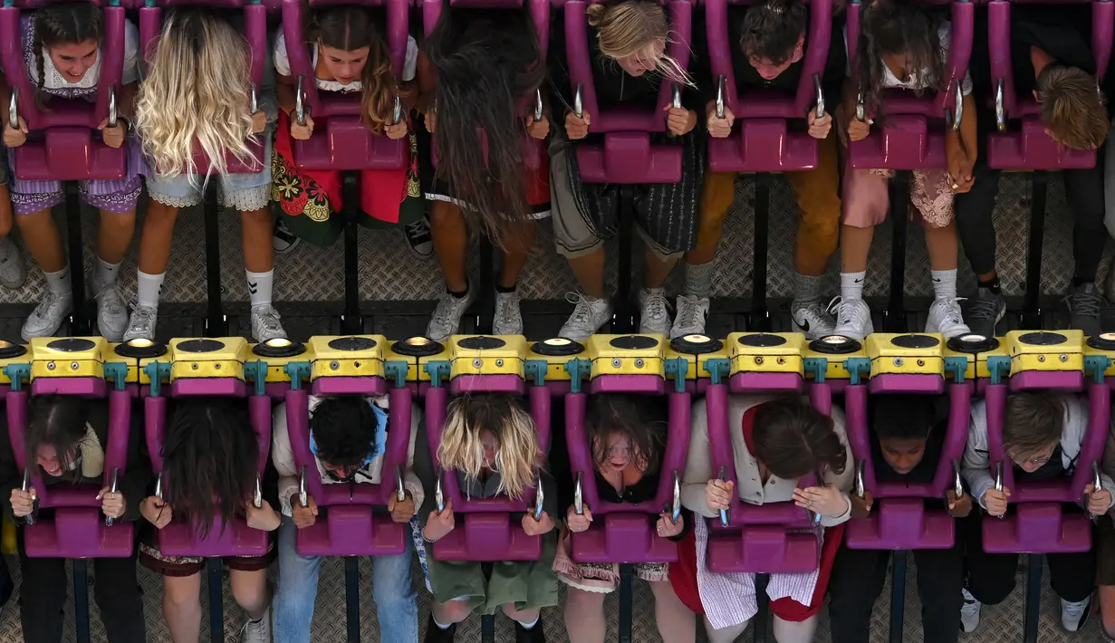 Pengunjung menikmati wahana pameran selama festival bir Oktoberfest di Theresienwiese di Munich, Jerman selatan (20/9/2022). Festival Bir yang terkenal di dunia ini akan berlangsung hingga 3 Oktober 2022 tanpa batasan akses, setelah dua hari terakhir edisi tahun telah dibatalkan karena pandemi coronavirus. (AFP/Christof Stache)