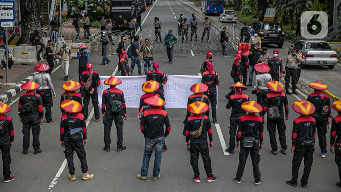 Massa aksi yang tergabung dalam Serikat Pekerja Indonesia (KSPI) membawa spanduk dan poster saat unjuk rasa di kawasan Patung Kuda, Jakarta, Rabu (16/12/2020). (Liputan6.com/Faizal Fanani)