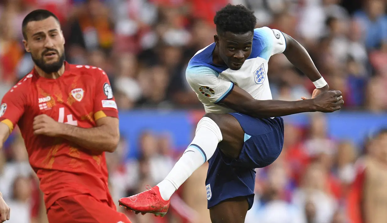 Gelandang Timnas Inggris, Bukayo Saka melepaskan tendangan yang berbuah gol ke gawang Makedonia Utara pada laga Grup C Kualifikasi Euro 2024 di Old Trafford, Manchester (19/6/2023). Bukayo Saka hingga kini telah mencetak total 11 gol dari 28 laga bersama Timnas Inggris sejak melakukan debut pada 8 Oktober 2020. Gol terakhirnya dibuat dengan mencetak hattrick saat Inggris menang 7-0 atas Makedonia Utara pada laga Grup C Kualifikasi Euro 2024. Hattrick tersebut menjadi hattrick pertama sepanjang karier baik bersama klub maupun timnas. (AFP/Oli Scarff)