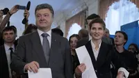 Presiden Ukraina Petro Poroshenko (kiri) dan istrinya Maria (kanan), memberikan suara di tempat pemungutan suara selama pemilihan presiden di Kiev, 25 Mei 2014. (AP/SergeiChuzavkov)