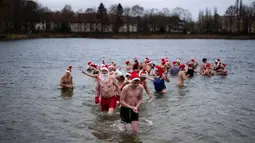 Para anggota klub renang "Berliner Seehunde" (Berlin Seals) berenang di Danau Orankesee yang dingin di Berlin, Jerman, Senin (25/12). Berenang di danau itu salah satu tradisi masyarakat Berlin menyambut Natal setiap tahun. (AP/Markus Schreiber)