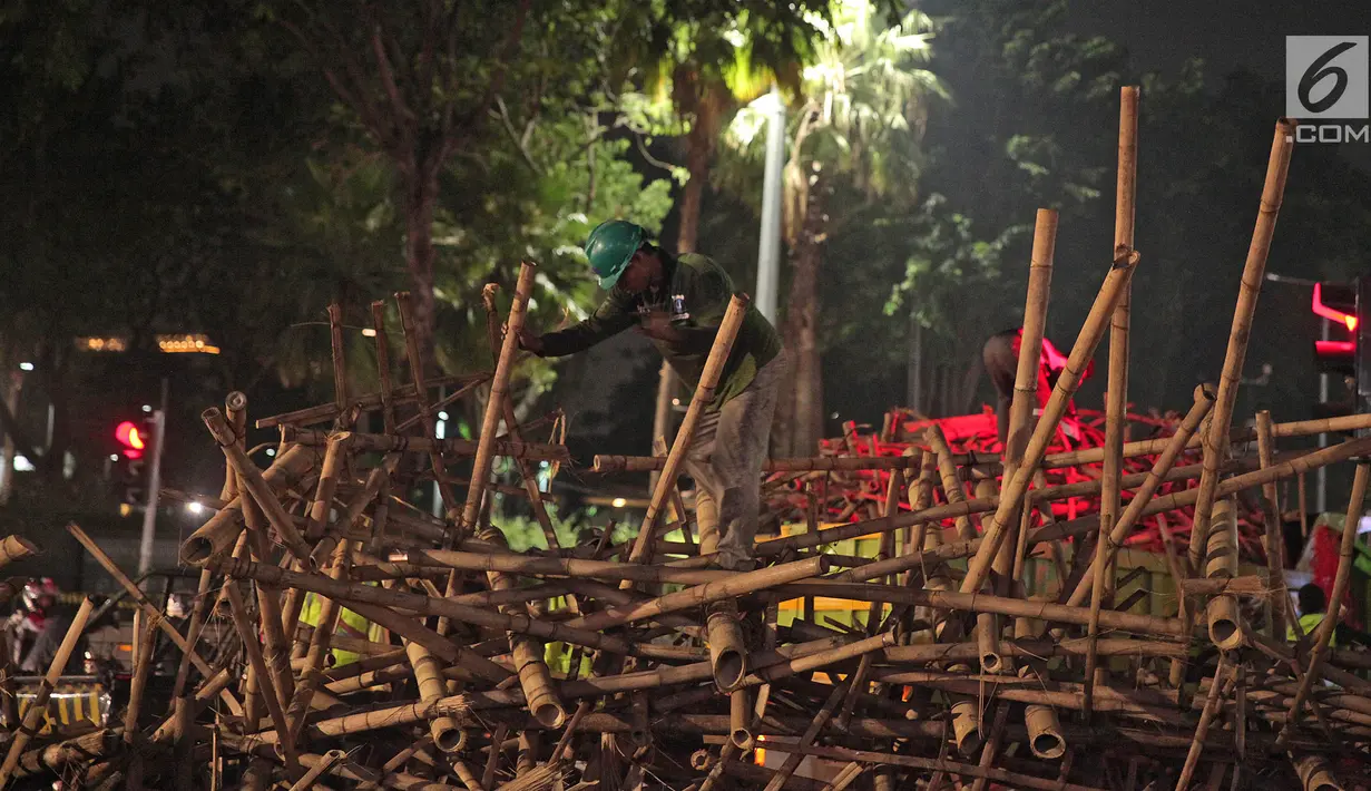 Petugas Dinas Kehutanan DKI Jakarta membongkar instalasi bambu Getah Getih di Bundaran Hotel Indonesia (HI), Kamis (18/7/2019) dini hari. Karya seni tersebut rencananya akan diganti dengan taman dan setelah dibongkar, bambu itu akan dibawa ke tempat pembuangan sampah. (Liputan6.com/Herman Zakharia)