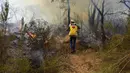 <p>Seorang petugas pemadam kebakaran berupaya memadamkan kebakaran hutan yang disebabkan suhu ekstrem di Larache, Maroko utara, Jumat (15/7/2022). Petugas pemadam kebakaran dan militer berjuang untuk menahan beberapa kebakaran hutan di Maroko utara, ketika ratusan warga mengungsi dari rumah mereka karena kobaran api yang melanda petak besar hutan pinus. (AP Photo)</p>