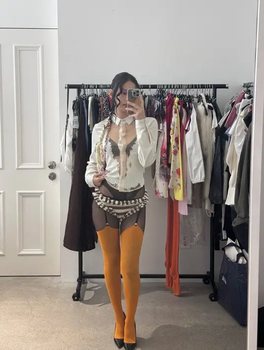 Ia juga memakai blus tipis yang memperlihatkan bra hitamnya, dipadukan dengan sheer pants atau celana terawang yang memperlihatkan underwear, serta stoking orange dan garter.  [@jennierubyjane].