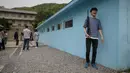 Pengunjung berpose memegang senapan tiruan saat mengunjungi replika desa perbatasan zona demiliterisasi (DMZ) Panmunjom di Namyangju, Korea Selatan, Sabtu (5/5). Replika Panmunjom itu  menjadi wisata baru setelah berlangsungnya KTT Korea. (AFP/Ed JONES)