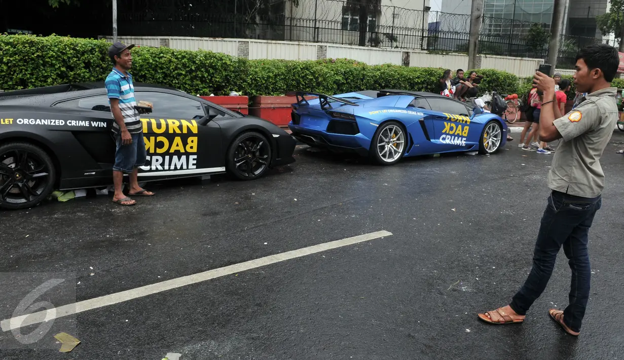 Sejumlah warga melakukan foto di samping mobil Lamborghini di Bundaran HI, Jakarta, Minggu  (29/11/2015). Dua Lamboghini ini sengaja parkir untuk kampanye memerangi kejahatan karena di Ibukota. (Liputan6.com/Johan Tallo)
