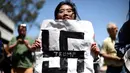 Seorang demonstran membawa poster bergambar Nazi saat demo menolak Donald Trump di Burlingame, California (29/4). Para wanita ini  menolak Donald Trump menjadi Presiden Amerika Serikat. (REUTERS/Noah Berger)