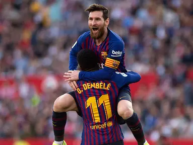 Penyerang Barcelona Lionel Messi memeluk rekan setimnya Ousmane Dembele usai mencetak gol ke gawang Sevilla pada laga La Liga di Stadion Ramon Sanchez Pizjuan, Sevilla, Sabtu (23/2). Barcelona menang 4-2. (JORGE GUERRERO/AFP)
