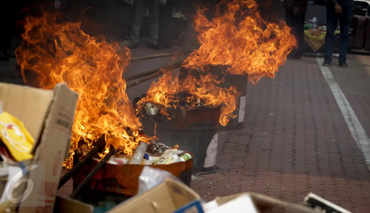 Sejumlah barang bukti dibakar saat pemusnahan di Kejaksaan Negeri Jakarta Utara, Kamis (16/3). 560 buah pangan tanpa izin edar, 450 buah kosmetik tanpa izin edar, dan 250 ini HP, baju, dan tas juga ikut dimusnahkan. (Liputan6.com/Faizal Fanani)