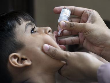 Petugas kesehatan memberikan vaksin polio kepada seorang anak selama kampanye vaksinasi polio dari pintu ke pintu di daerah kumuh di Karachi, Paksistan, Senin (23/5/2022). Pakistan meluncurkan upaya anti-polio baru pada hari Senin, lebih dari seminggu setelah pejabat mendeteksi kasus ketiga tahun ini di wilayah barat laut negara itu yang berbatasan dengan Afghanistan. (Asif HASSAN / AFP)