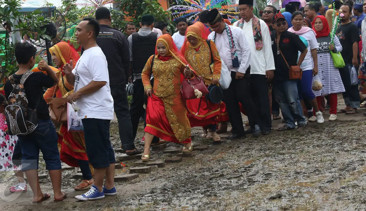 Pengunjung menghindari jalan yang becek pada Festival Lebaran Betawi IX, Jakarta, (14/8). Festival diramaikan dengan rumah adat Betawi dari masing-masing pemkot  administrasi Jakarta serta Kabupaten Kepulauan Seribu. (Liputan6.com/Immanuel Antonius)