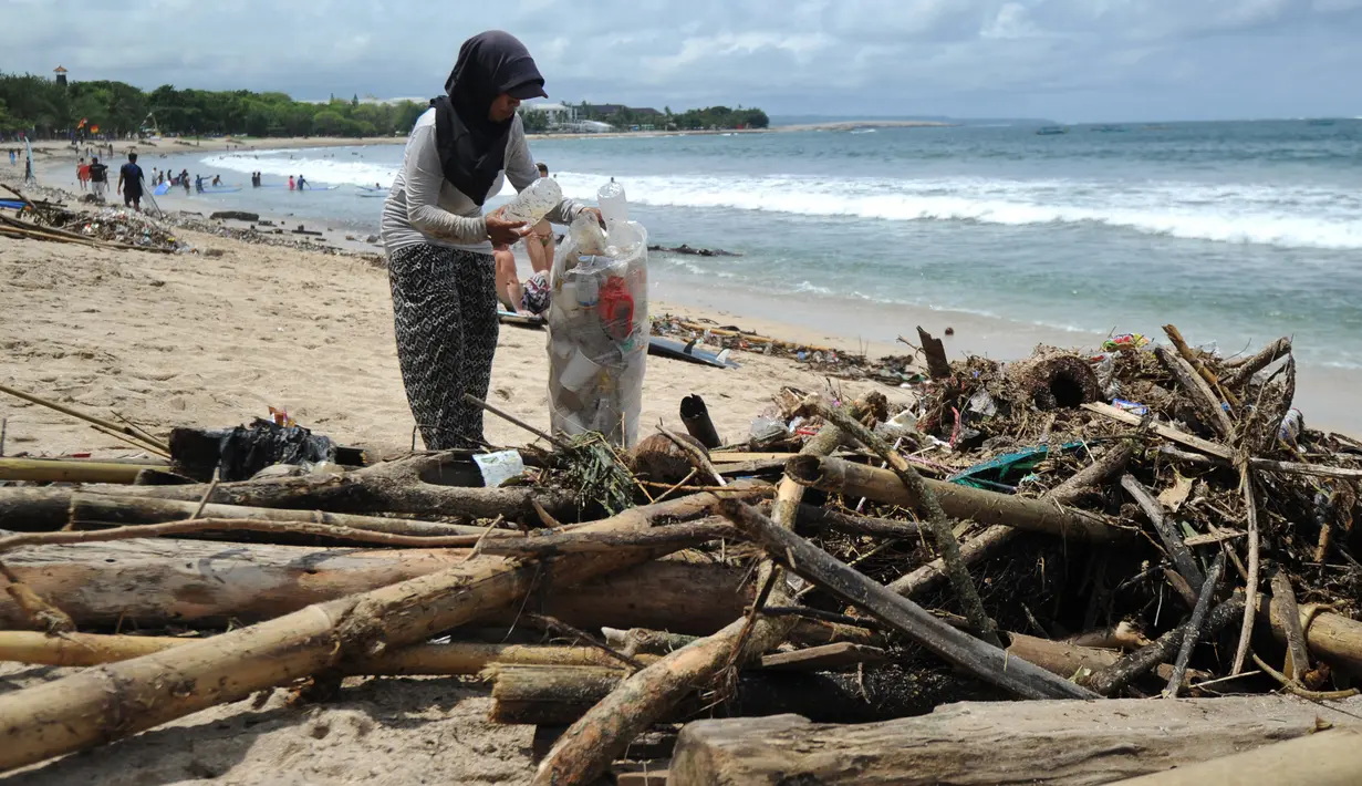 Seorang pengumpul sampah mengambil botol plastik dari puing-puing dan sampah di pesisir Pantai Kuta, Bali, Minggu (9/12). Kawasan pantai Kuta kembali dipenuhi oleh sampah hanyut terbawa oleh gelombang. (SONNY TUMBELAKA / AFP)