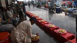 Seorang nelayan menyiapkan makanan berbuka puasa selama bulan suci Ramadhan di galangan kapal di kota pelabuhan Karachi Pakistan pada 18 April 2022. Setelah menjalani ibadah puasa, waktu buka puasa menjadi momen yang dinanti oleh umat Islam. (Rizwan TABASSUM / AFP)