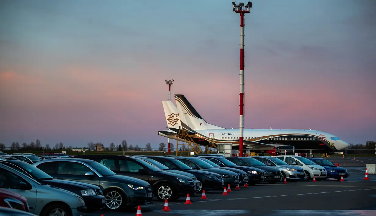 Orang-orang duduk di mobil mereka saat menonton film di bioskop drive-in di area apron bandara kota Vilnius, Lithuania, 29 April 2020. Untuk pertama kalinya dalam sejarah bandara Vilnius mengadakan bioskop drive-in yang beroperasi di tempat pesawat lepas landas dan mendarat. (AP/Mindaugas Kulbis)