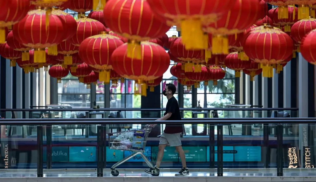 Seorang pembeli berjalan di lorong mal dengan dekorasi lentera untuk perayaan Tahun Baru Imlek di Kuala Lumpur, Malaysia, Rabu (3/2/2021). Imlek tahun ini jatuh pada tanggal 12 Februari 2021. (Mohd RASFAN/AFP)