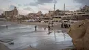 Warga Palestina menata kembali kehidupan mereka di antara puing-puing kehancuran akibat serangan yang dilancarkan Israel sejak Okrober 2023 silam. Tampak dalam foto, seorang peselancar Palestina membawa papan selancarnya ke laut di sepanjang garis pantai di Kota Gaza, Minggu, 28 Desember 2025. (AP Photo/Jehad Alshrafi)