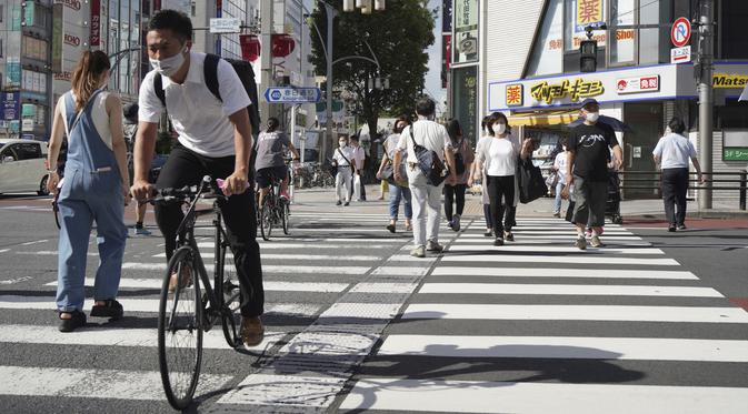 Seorang pria yang mengenakan masker untuk membantu mengekang penyebaran virus corona COVID-19 mengendarai sepeda di Tokyo, Jepang, Jumat (6/8/2021). Tokyo berada dalam keadaan darurat virus corona COVID-19 sejak pertengahan Juli. (AP Photo/Kantaro Komiya)