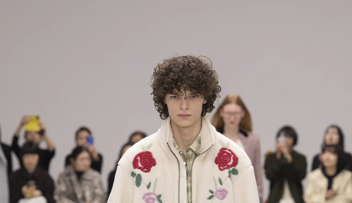 Di atas runway, koleksi menampilkan perpaduan formalwear, casualwear, workwear, dan sportswear yang menghasilkan kombinasi baru yang tak terduga. Gaun dengan aksen pita horizontal dipadukan hoodie bermotif herringbone, sementara gaun plisket hijau apel tampil kontras dengan rompi korduroi bertekstur dan kantong besar. Look lain menghadirkan blus kotak kotak ringan dengan motif bunga yang dipadukan rok midi kuning oker berbahan menyerupai bulu serta pita biru langit di pinggang. Nuansa romantis juga muncul melalui fleece hijau apel yang dikenakan di atas blus merah muda berpita, dipadukan rok mini rajut. [Dok/Onitsuka Tiger].