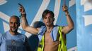 Pemain Manchester City, Jack Grealish (kanan), memasuki panggung dengan mengenakan rompi proyek setelah melakukan parade Treble Winners, Selasa (13/6/2023) dini hari WIB. Pep Guardiola hanya bisa tersenyum melihat kelakuan anak asuhnya tersebut. (AFP/Oli Scarff)