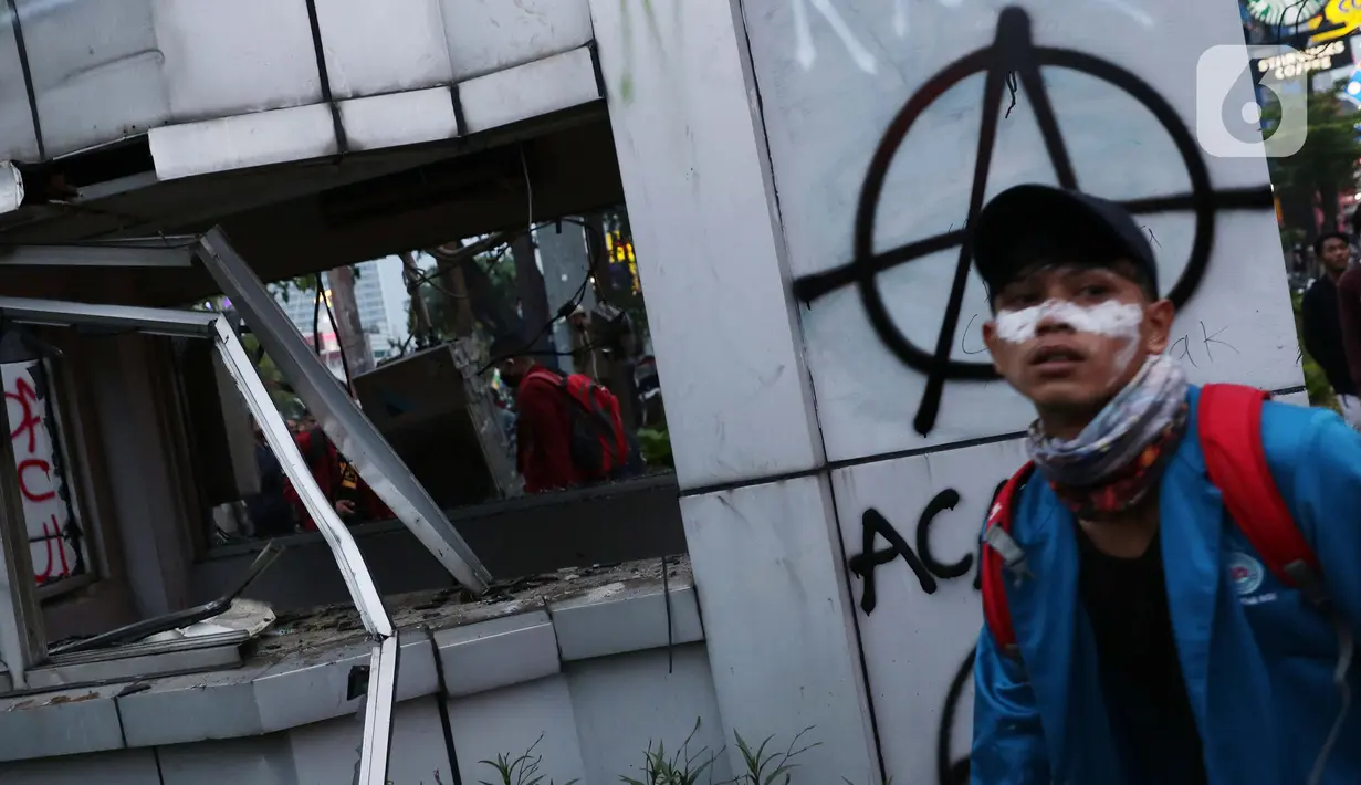Seorang mahasiswa melintasi Pos Polisi yang dirusak massa di kawasan Gondangdia, Jakarta, Kamis (8/10/2020). Aksi anarkis massa dilakukan saat berunjuk rasa menentang disahkan Omnibus Law UU Cipta Kerja. (Liputan6.com/Helmi Fithriansyah)