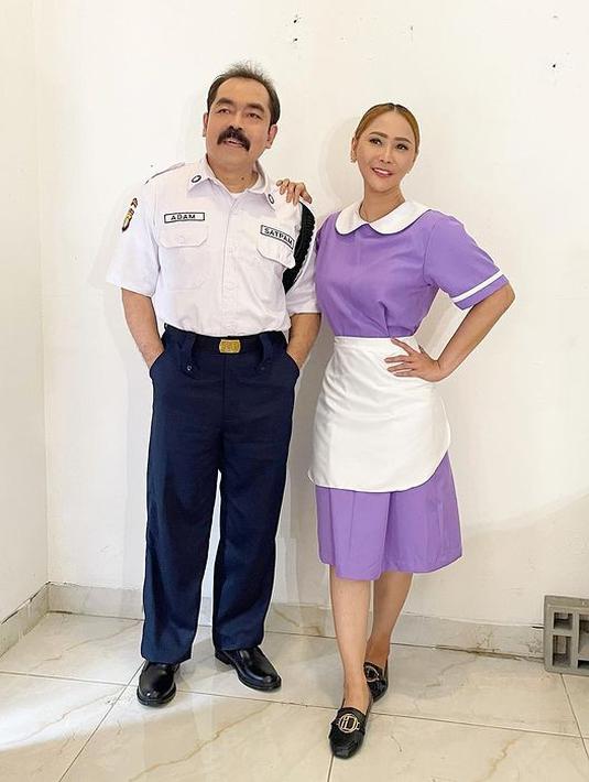 Adam Suseno kali ini menjadi petugas keamanan alias sekuriti di sebuah rumah mewah. Ia tampil rapi dengan kemeja putih lengan pendek dan celana panjang biru dongker. Sang Ratu Ngebor rupanya jadi asisten rumah tangga dengan atasan dan rok warna kecubung. Agar tak terkesan monoton, pada bagian kerah, lengan, dan celemeknya diwarnai putih. (Foto: Dok. Instagram @inul.d)