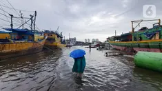 Nelayan melintasi banjir rob saat cuaca ekstrem di Pelabuhan Muara Baru, Penjaringan, Jakarta Utara, Rabu (28/12/2022). Banjir ROB, hujan deras dan  cuaca buruk melanda kawasan Pelabuhan Muara Baru saat siang menjelang sore hari. (Liputan6.com/Johan Tallo)