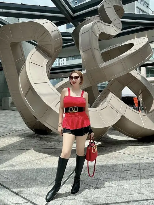 Knee boots hitamnya pun dipadukan dengan atasan merah serta short pants hitam. Dengan detail belt hitam besar. (@femmypermatasari)
