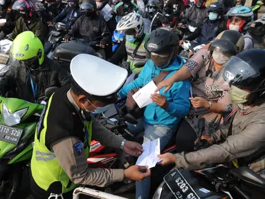 Petugas polisi memeriksa kelengkapan Surat Tanda Registrasi Pekerja  (STRP) bagi pengendara bermotor pada pos  perpanjangan Pemberlakuan Pembatasan Kegiatan Masyarakat (PPKM) Jalan Raya Ir.H.Djuanda, depan Sandratex, Tangerang Selatan, Kamis (15/07/2021). (merdeka.com/Arie Basuki)