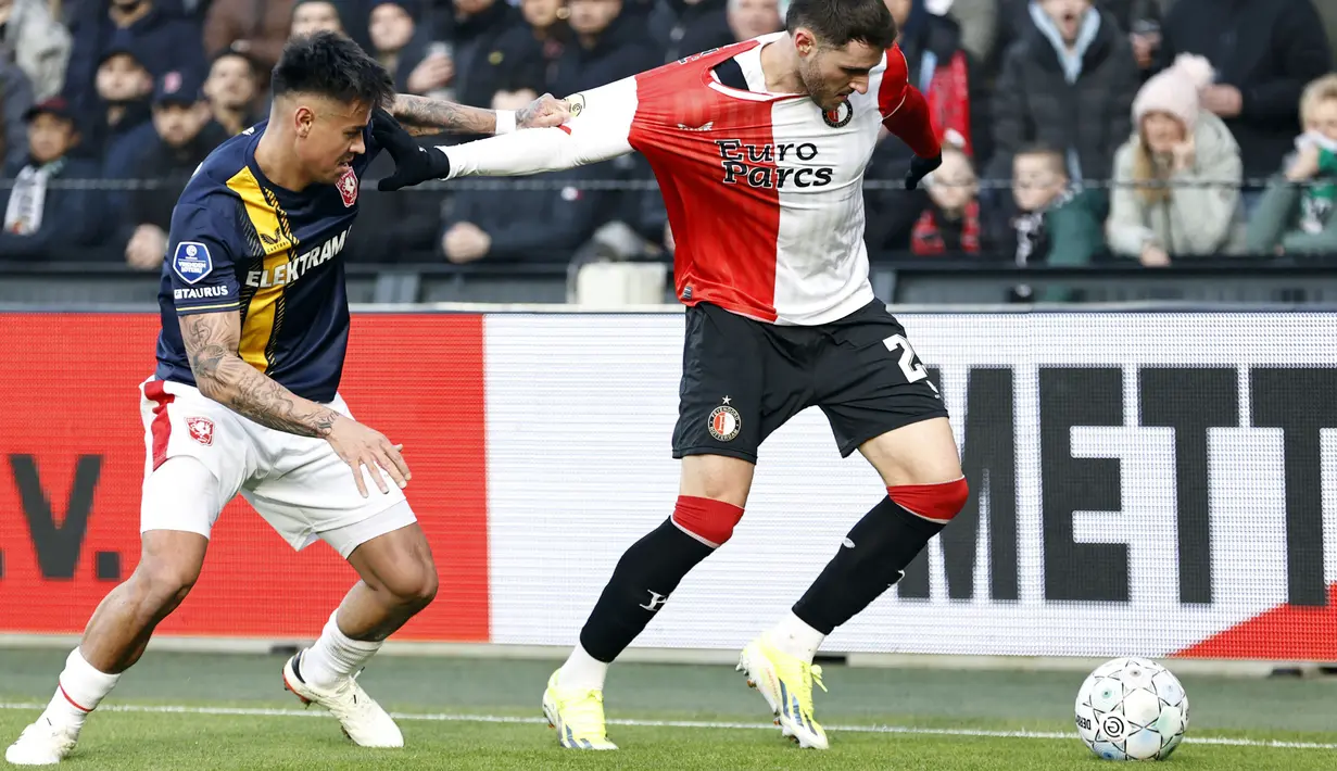 Pemain Twente, Mees Hilgers (kiri) berusaha merebut bola dari pemain Feyenoord, Santiago Gimenez pada laga lanjutan Liga Belanda 2023/2024 yang berlangsung di Feyenoord Stadion de Kuip, Rotterdam, Belanda, 28 Januari 2024. (AFP/ANP/Maurice Van Steen)