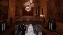 Petugas berjaga dekat gaun pernikahan Meghan Markle dan Pangeran Harry yang ditampilkan pada pameran “A Royal Wedding: The Duke and Duchess of Sussex” di Kastil Windsor, London, 25 Oktober 2018. Pameran ini dibuka hingga Januari 2019. (AP/Matt Dunham)