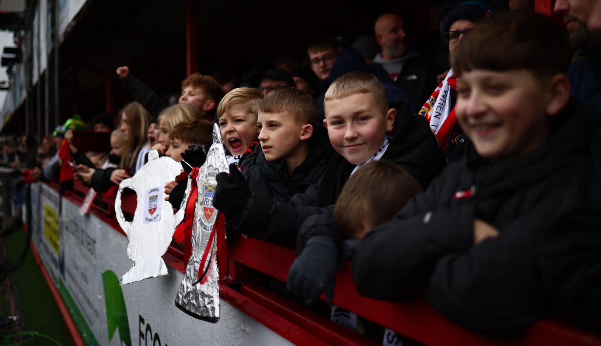 Sejumlah pendukung Tamworth memadati tribune pada laga Piala FA 2024/2025 melawan Tottenham Hotspur di The Lamb Ground, Tamworth, Inggris, Minggu (12/01/2025) waktu setempat. (AFP/Henry Nicholls)