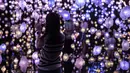 Seorang wanita mengambil foto "Pixel Forest" oleh seniman Swiss Pipilotti Rist, instalasi seni dari 3000 lampu LED pahatan tangan yang digantung di langit-langit di Tai Kwun di Hong Kong (18/8/2022). (AFP/Isaac Lawrence)