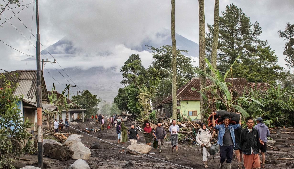 Orang-orang berjalan di tanah yang tertutup abu vulkanik setelah aliran piroklastik selama letusan Gunung Semeru di Desa Supiturang, Lumajang, Jawa Timur pada Kamis 20 November 2025. Gunung Semeru kembali mengalami erupsi pada Rabu (19/11/2025) sore. (Agus Harianto/AFP)