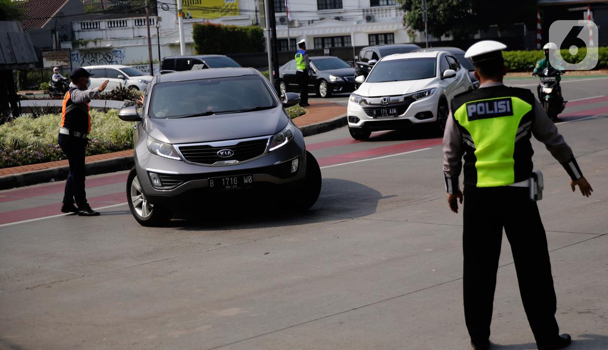 Petugas polisi mengarahkan kendaraan berplat nomor genap di pos penyekatan ganjil-genap di Bundaran Senayan, Minggu (5/9/2021). Pembatasan kendaraan dengan sistem pelat nomor kendaraan ini tetap berlaku di akhir pekan, Sabtu dan Minggu. (Liputan6.com/Angga Yuniar)