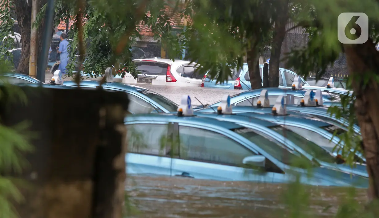 Sejumlah taksi terendam banjir di Pool Taksi Bluebird kawasan Kramat Jati, Jakarta, Selasa (25/2/2020). Meluapnya Kali Cipinang membuat Pool Taksi Blue Bird yang berada tepat di samping kali ikut terdampak banjir. (Liputan6.com/Herman Zakharia)