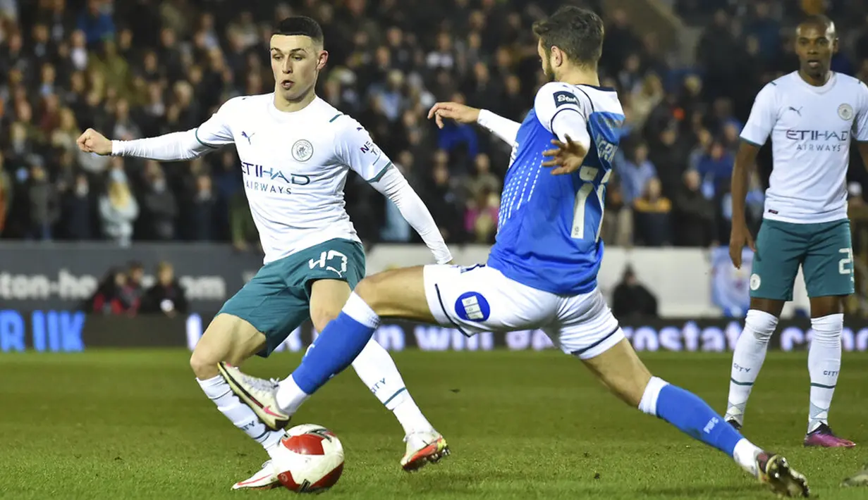 Pemain Manchester City Phil Foden (kiri) berebut bola dengan pemain Peterborough United Jorge Grant pada pertandingan sepak bola putaran kelima Piala FA di Stadion Weston Homes, Peterborough, Inggris, 1 Maret 2022. Manchester City menang 2-0. (AP Photo/Rui Vieira)