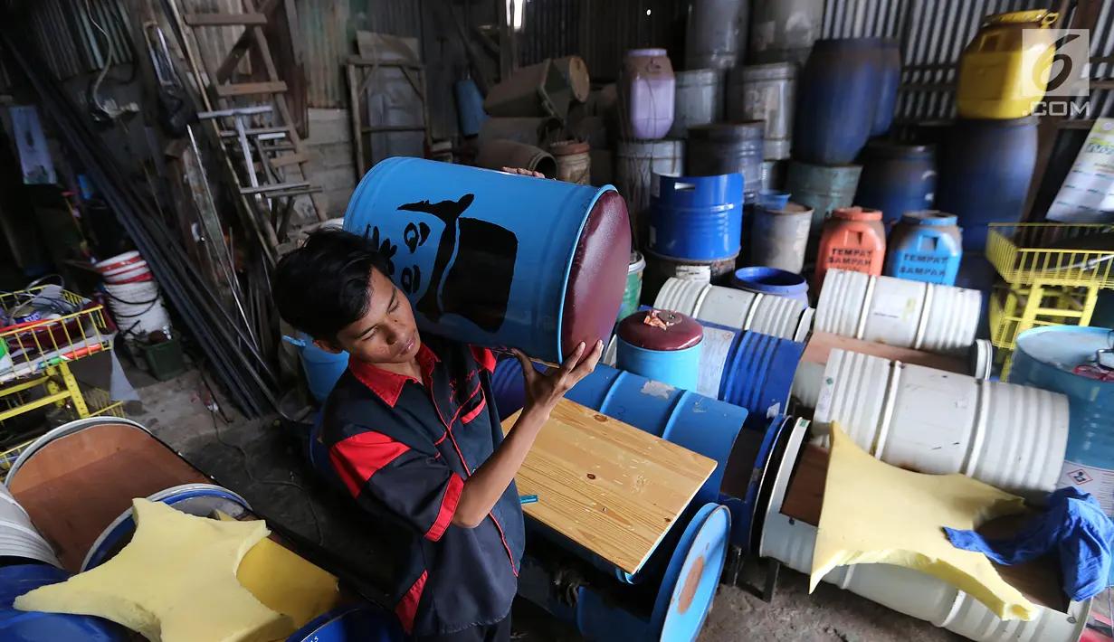 Pekerja sedang mengangkat bangku dari drum bekas di industri kecil Ali Kreatif, Parung Bogor, Selasa (30/1). Industri yang beromset 20 juta rupiah setiap minggunya juga memproduksi tempat sampah, lemari hingga meja. (Liputan6.com/Fery Pradolo)