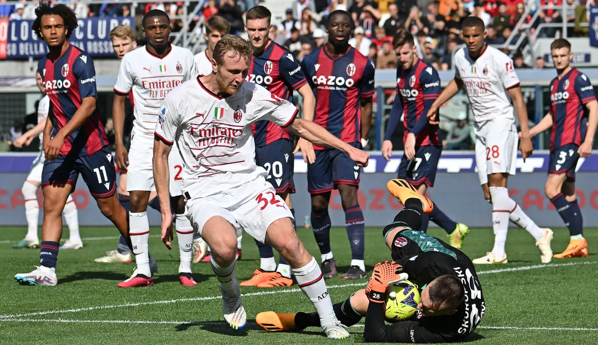Pemain AC Milan, Tommaso Pobega (tengah kiri) berusaha mencetak gol ke gawang Bologna yang dijaga Lukasz Skorupski pada laga lanjutan Liga Italia 2022/2023 di Renato-Dall'Ara Stadium, Bologna, Minggu (16/04/2023) WIB. Laga berakhir dengan skor imbang 1-1. (AFP/Alberto Pizzoli)