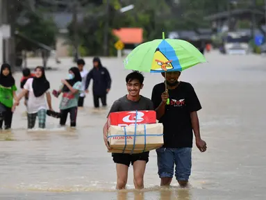 Warga berjalan melewati banjir menyusul hujan lebat di distrik Ran-ngea di provinsi Narathiwat, Thailand selatan (26/2/2022).  Hujan yang disebabkan oleh angin timur laut di atas Teluk Thailand terus berlanjut selama tiga hari berturut-turut di provinsi perbatasan selatan ini. (AFP/Madaree Tohlala)